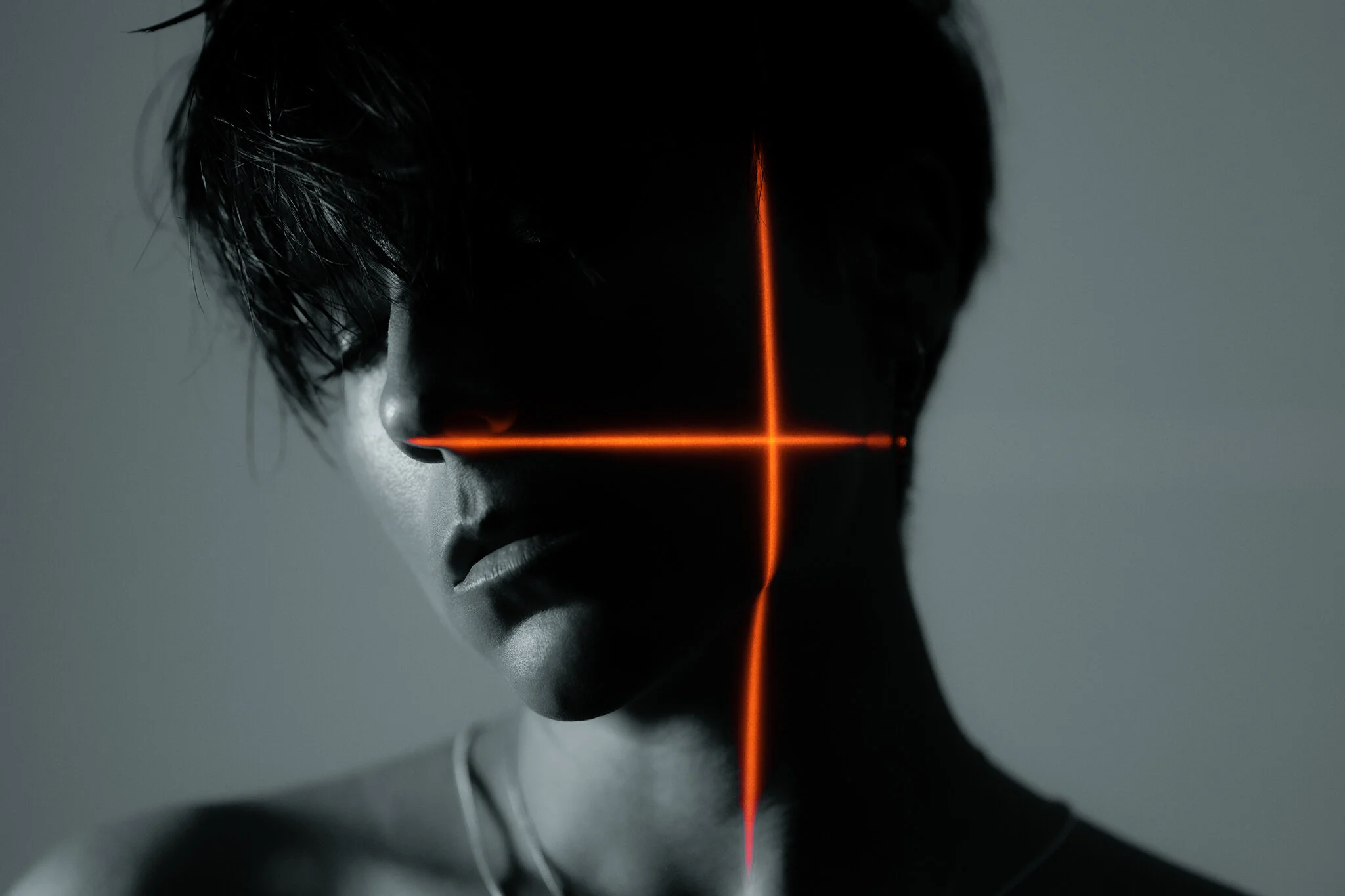 Portrait Winner February - A person with an orange cross of light shining on them in a black and white scene